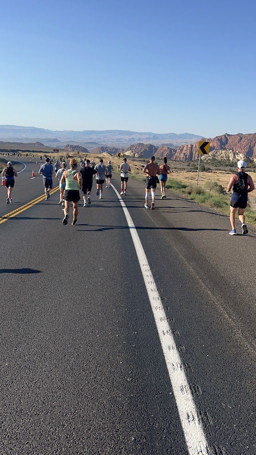Group of runners jogging down a sunlit road, representing the connection between hydration and mental health